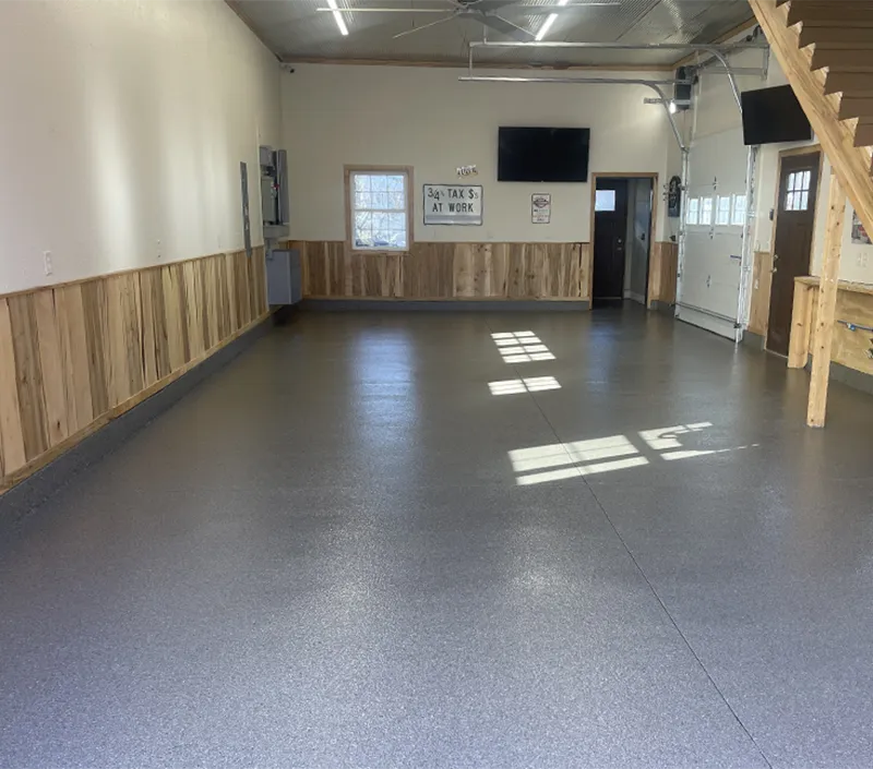 Polyaspartic concrete floor coating in speckled flaked gray color with color quartz broadcast , featuring the fast 1-day installation.